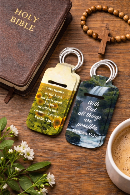 Scripture ChapStick Holder Keychains featuring Bible verses with mountain and nature backgrounds. Includes Psalm 136:1, 1 Corinthians 16:14, 2 Timothy 1:7, Matthew 19:26, Isaiah 41:10, James 4:8, Psalm 120:1, and Philippians 4:13. Bible & Coffee Cup Pictured